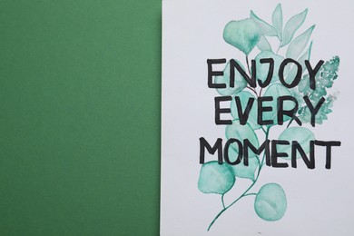Photo of Card with phrase Enjoy Every Moment on green background, top view. Space for text