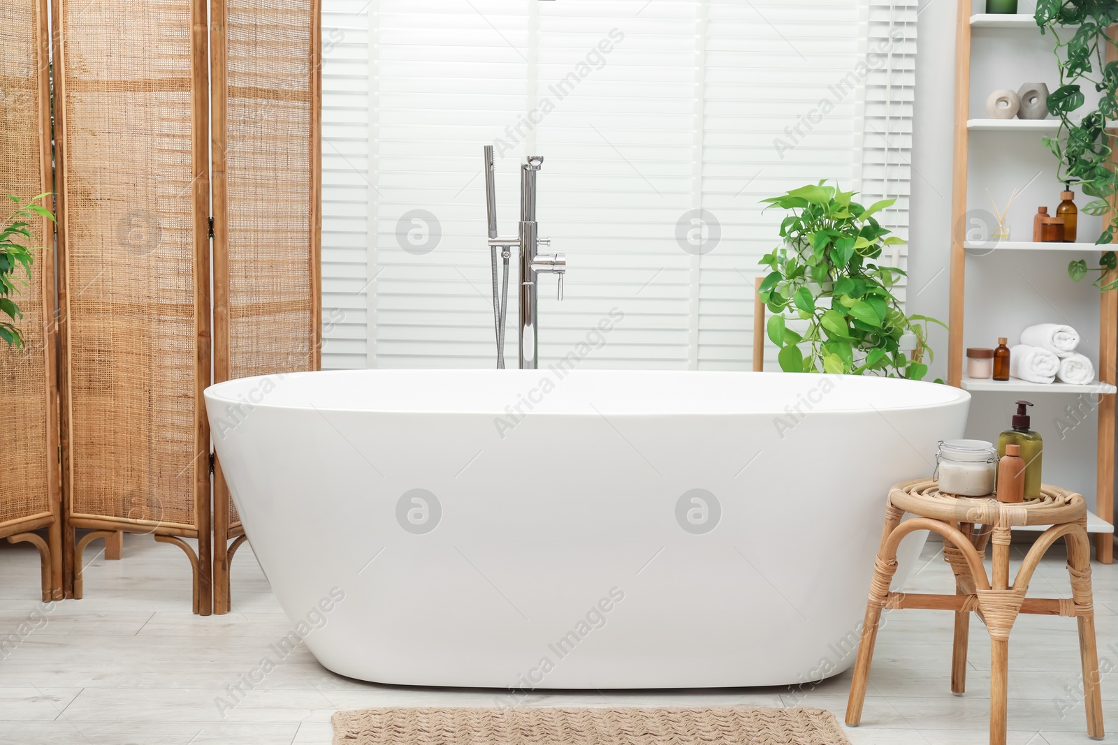 Photo of Spa day. Stylish bathroom interior with ceramic tub and green houseplants