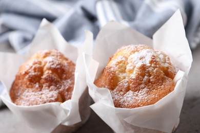 Photo of Delicious muffins with powdered sugar on grey table, closeup