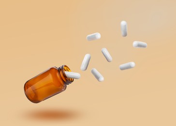 Image of Vitamin capsules flying out from bottle on pale orange background