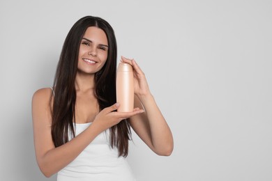 Photo of Beautiful young woman holding bottle of shampoo on white background, space for text