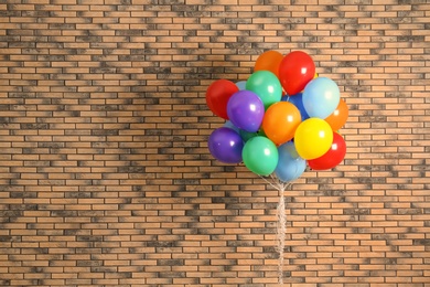 Bunch of bright balloons and space for text against brick wall