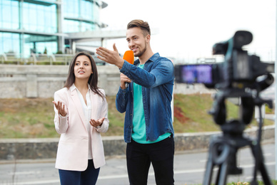 Photo of Young journalist interviewing businesswoman on city street