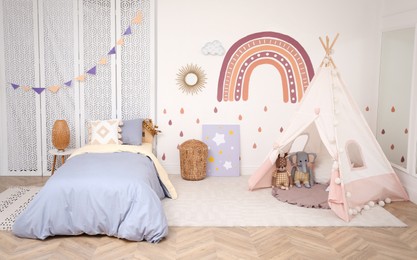 Photo of Stylish room with comfortable bed and teepee tent for kids. Interior design