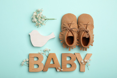 Flat lay composition with child's booties and word Baby on light blue background