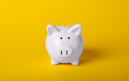 Ceramic piggy bank on yellow background. Financial savings