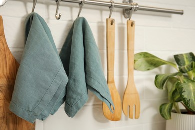 Photo of Clean towels and utensils hanging on rack in kitchen