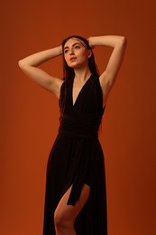 Photo of Beautiful woman in black dress posing on brown background