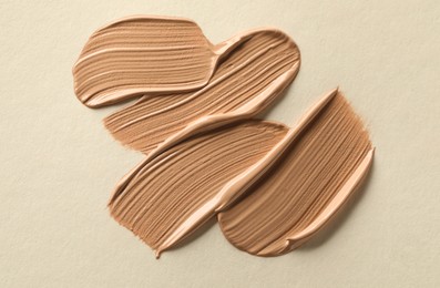 Photo of Sample of liquid skin foundation on beige background, top view