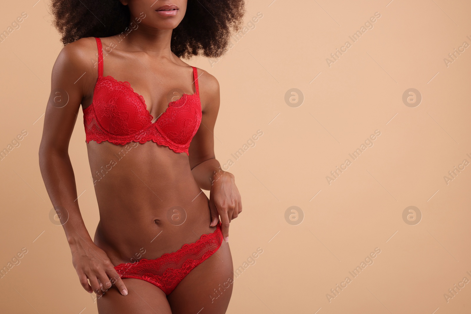 Photo of Woman in elegant red underwear on beige background, closeup. Space for text