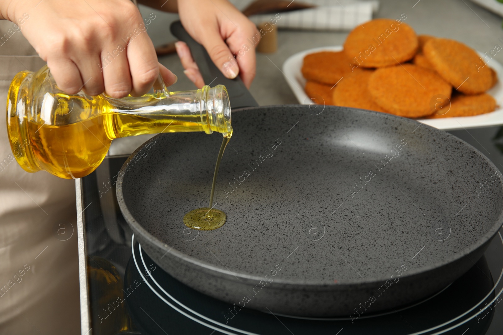 Photo of Woman adding oil on frying pan, closeup. Cooking breaded cutlets