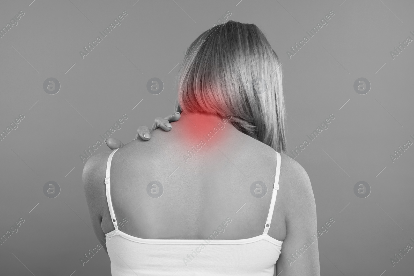 Image of Woman suffering from neck pain on grey background, black and white effect