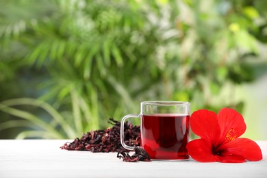 Delicious hibiscus tea and flowers on white wooden table outdoors, space for text