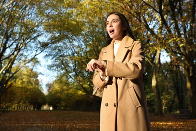 Photo of Emotional woman checking time on watch in park. Being late concept