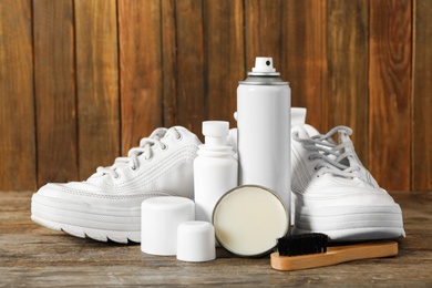 Composition with stylish footwear and shoe care accessories on wooden background