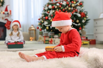 Cute little boy with toy car in room decorated for Christmas