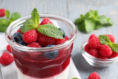 Photo of Delicious panna cotta with berries in glass dish, closeup
