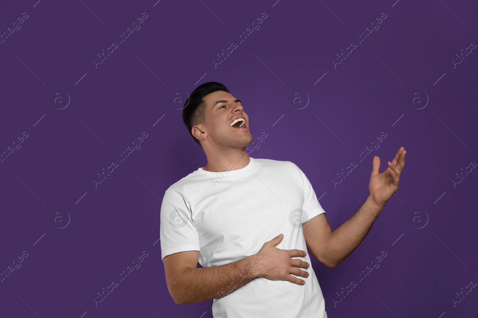 Photo of Handsome man laughing on purple background. Funny joke