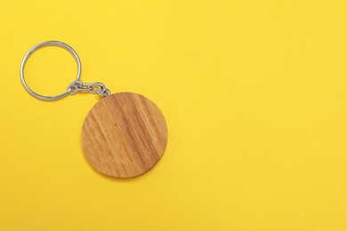 Photo of Wooden keychain in shape of smiley face on yellow background, top view. Space for text