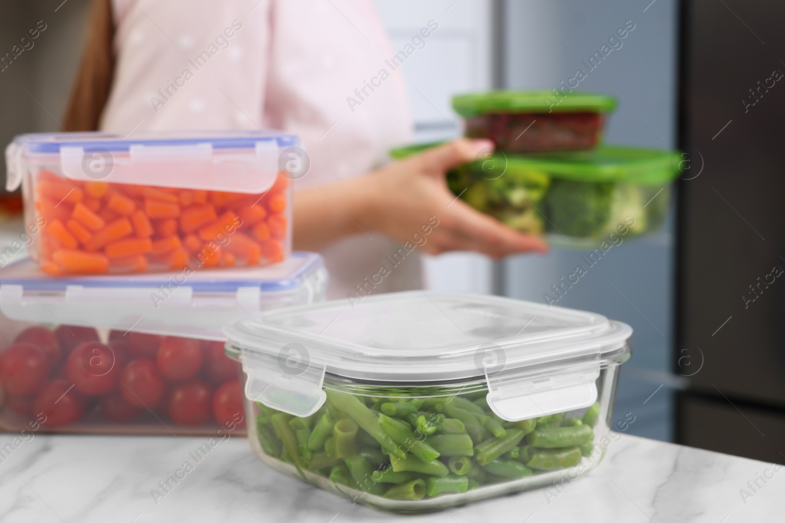 Photo of Glass and plastic containers with different fresh products on white marble table, selective focus