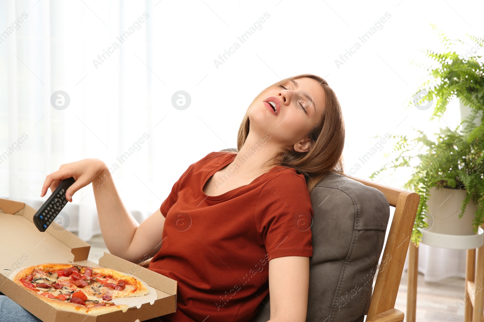 Photo of Lazy young woman with pizza and TV remote sleeping at home