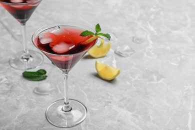 Photo of Glass of delicious cocktail with ice on light grey table. Space for text