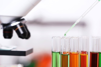 Photo of Dripping reagent into test tube with sample in chemistry laboratory, closeup. Space for text