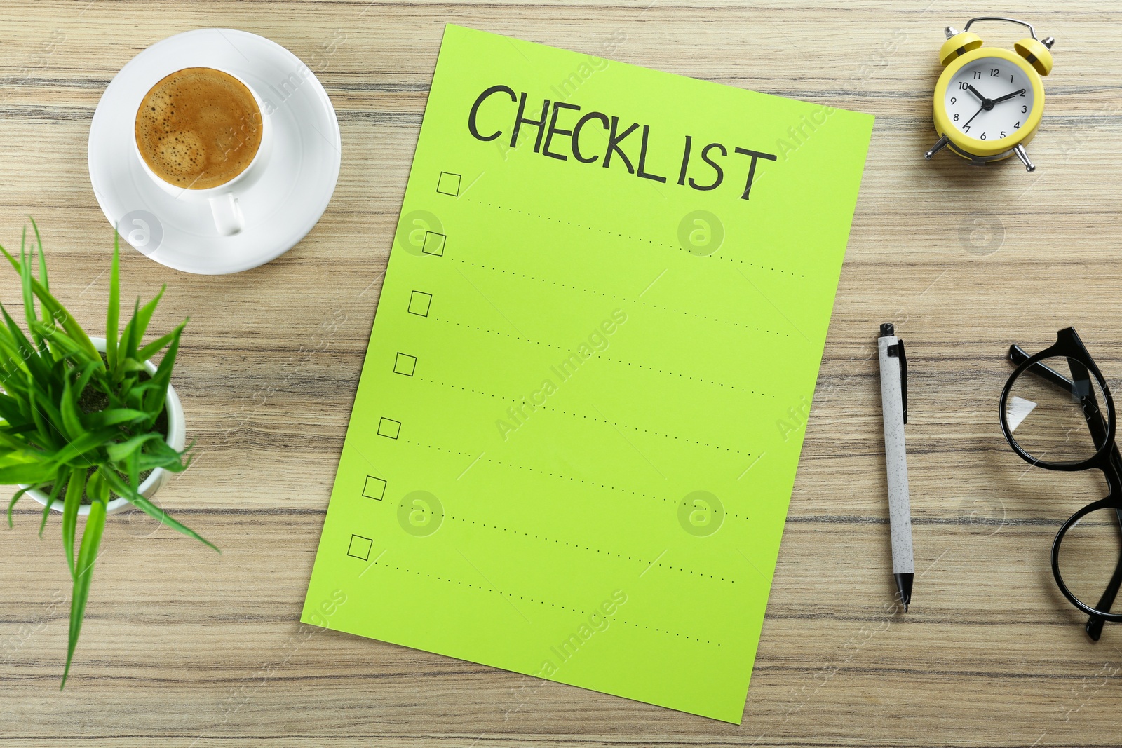 Photo of Paper sheet with inscription Checklist, alarm clock, plant, cup of coffee and eyeglasses on wooden table, flat lay