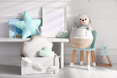 Empty photo frame and cute toys near wall in baby room. Interior design
