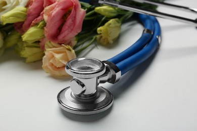 Stethoscope and flowers on white background, closeup. Happy Doctor's Day