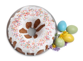 Glazed Easter cake with sprinkles, painted eggs and flowers on white background, top view