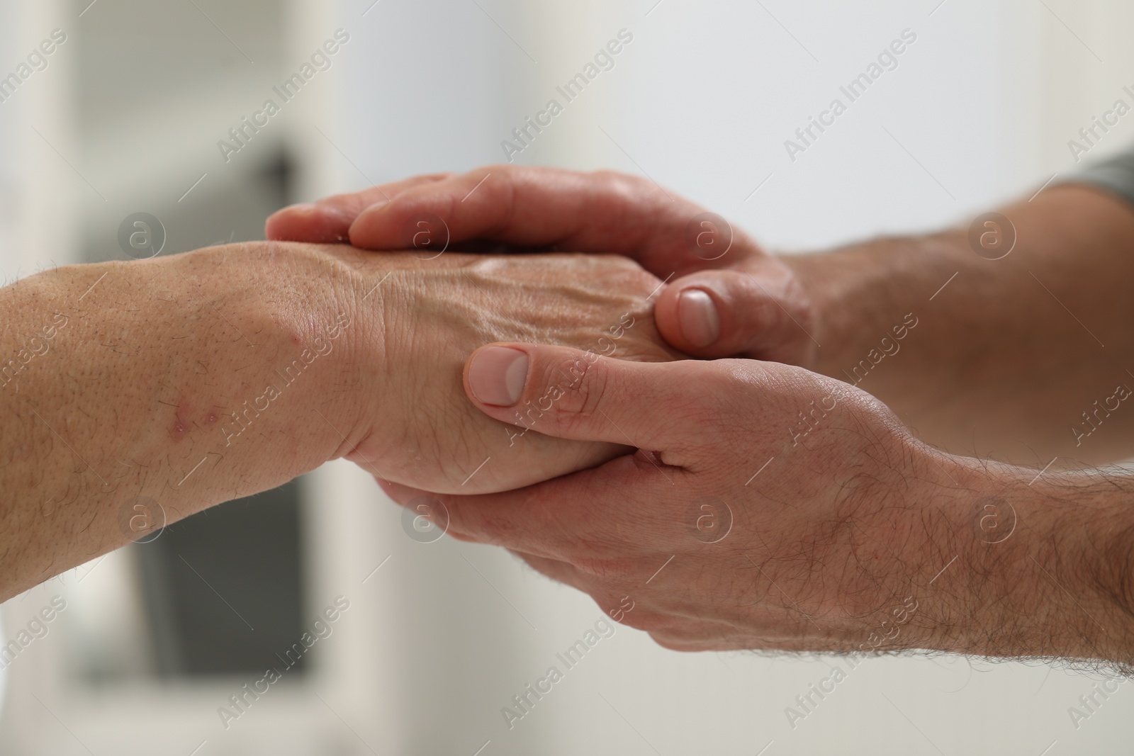 Photo of Trust and support. Men joining hands indoors, closeup