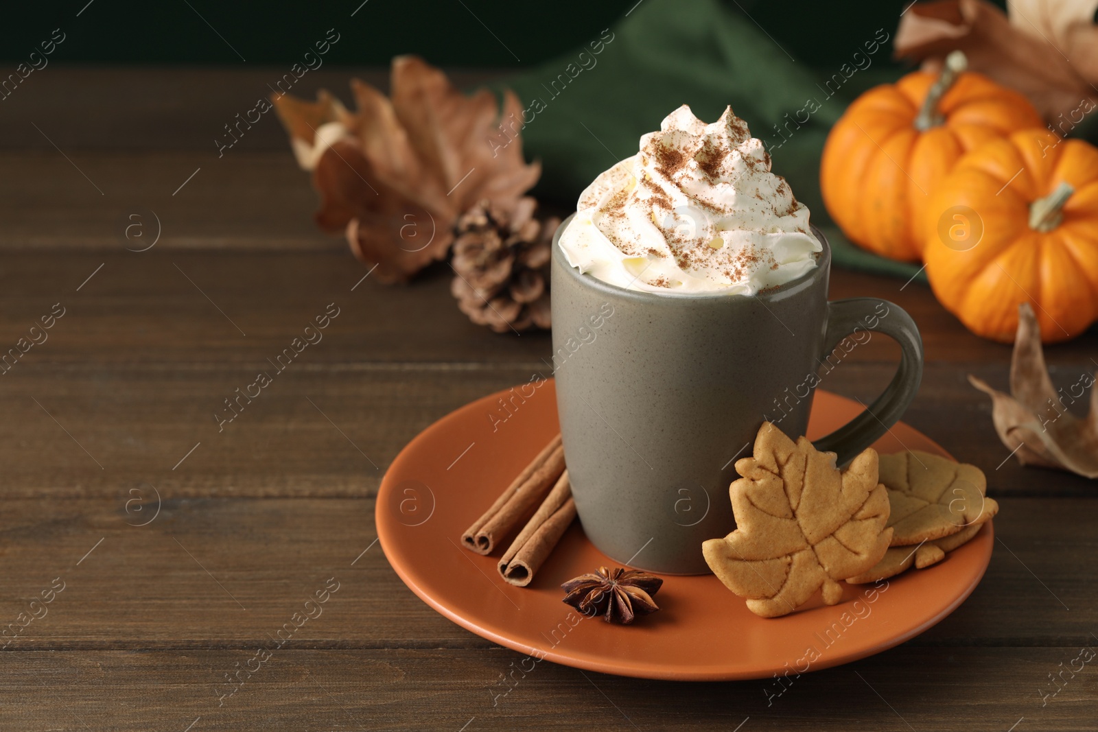 Photo of Tasty pumpkin spice latte with whipped cream in cup and cookies on wooden table. Space for text