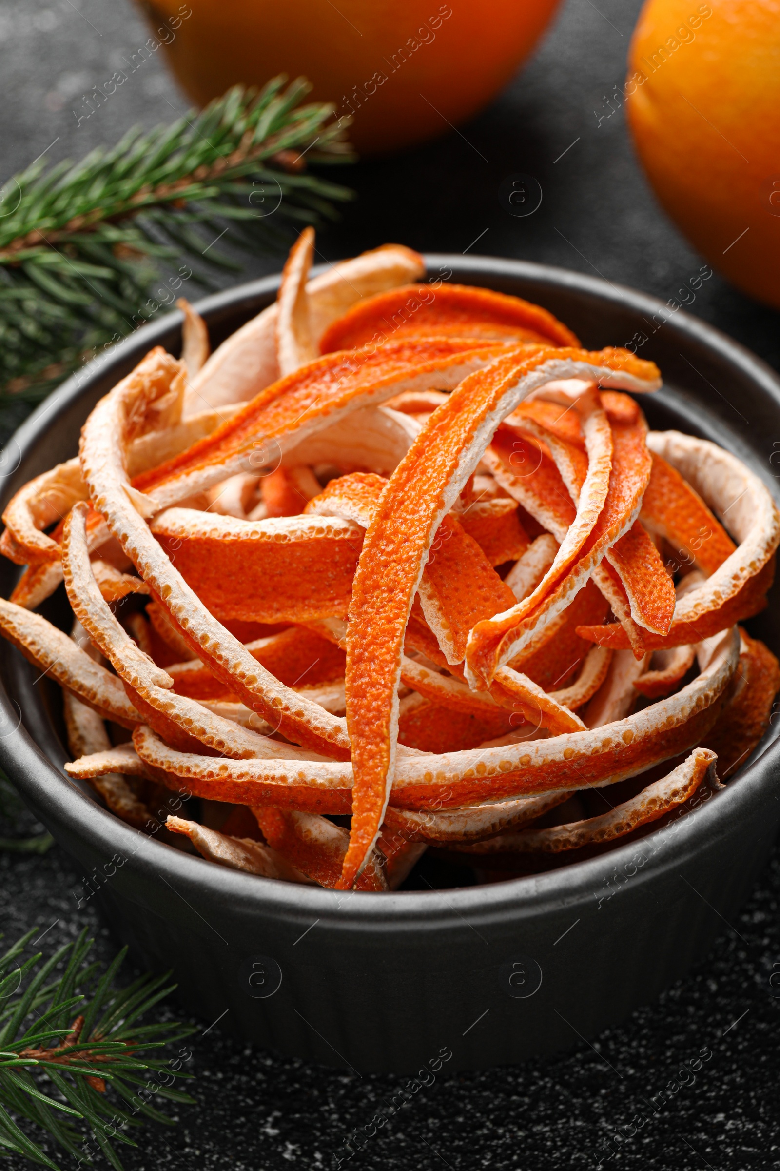 Photo of Dry peels, oranges and fir branch on gray textured table, closeup