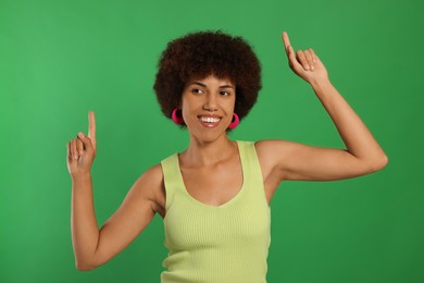 Photo of Happy young woman dancing on green background