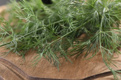 Photo of Fresh dill on wooden board, closeup view