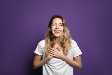 Photo of Cheerful young woman laughing on violet background