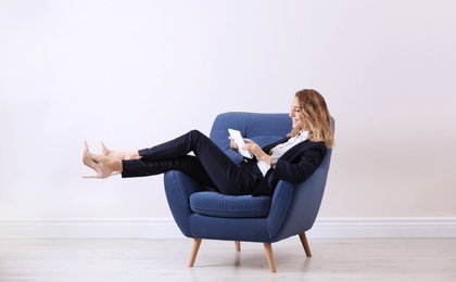 Photo of Young woman with tablet in armchair indoors
