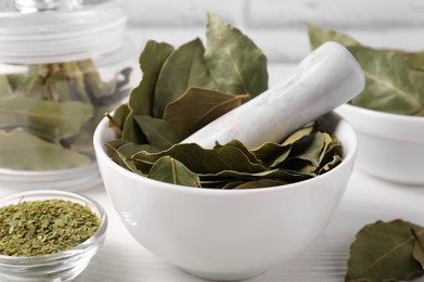 Photo of Whole and ground bay leaves on white wooden table, closeup