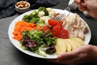 Photo of Balanced diet and healthy foods. Woman eating dinner at black table, closeup