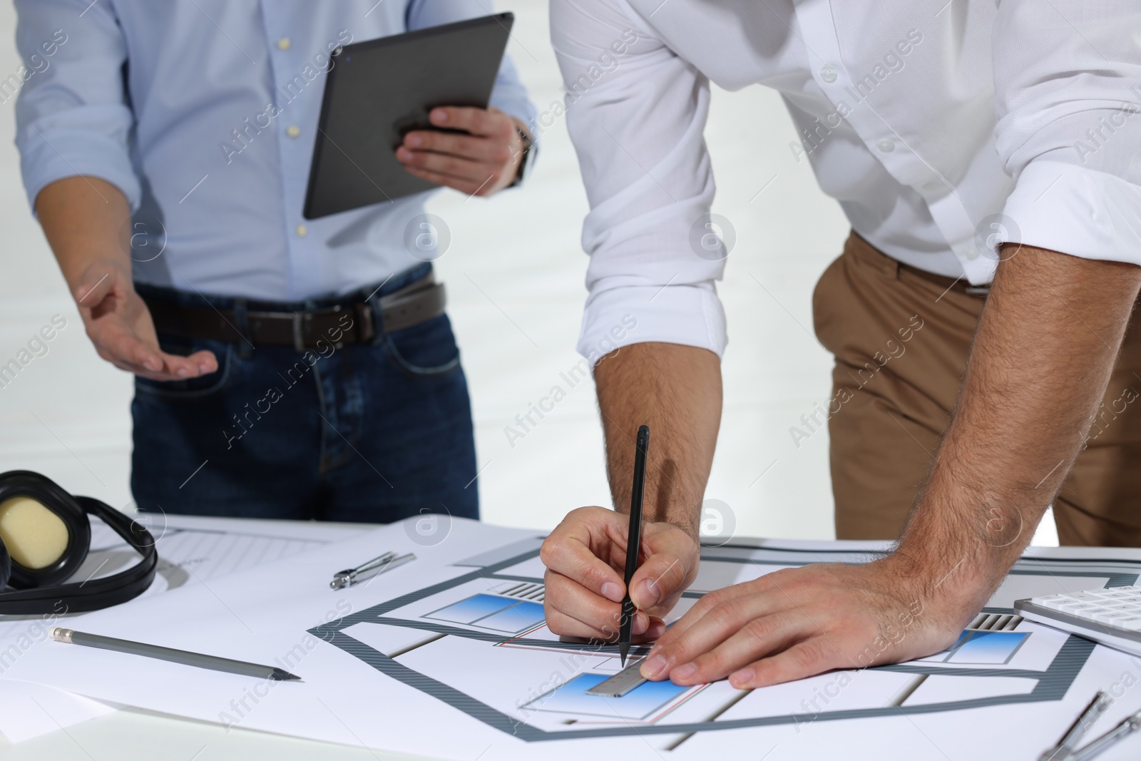 Photo of Architects working with construction drawings at table in office, closeup