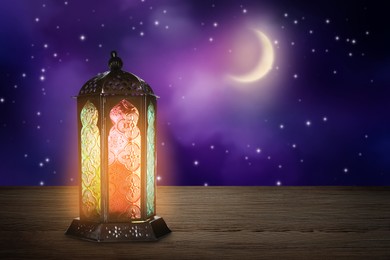 Image of Beautiful decorative Arabic lantern on wooden table at night, space for text. Fanous as Ramadan symbol