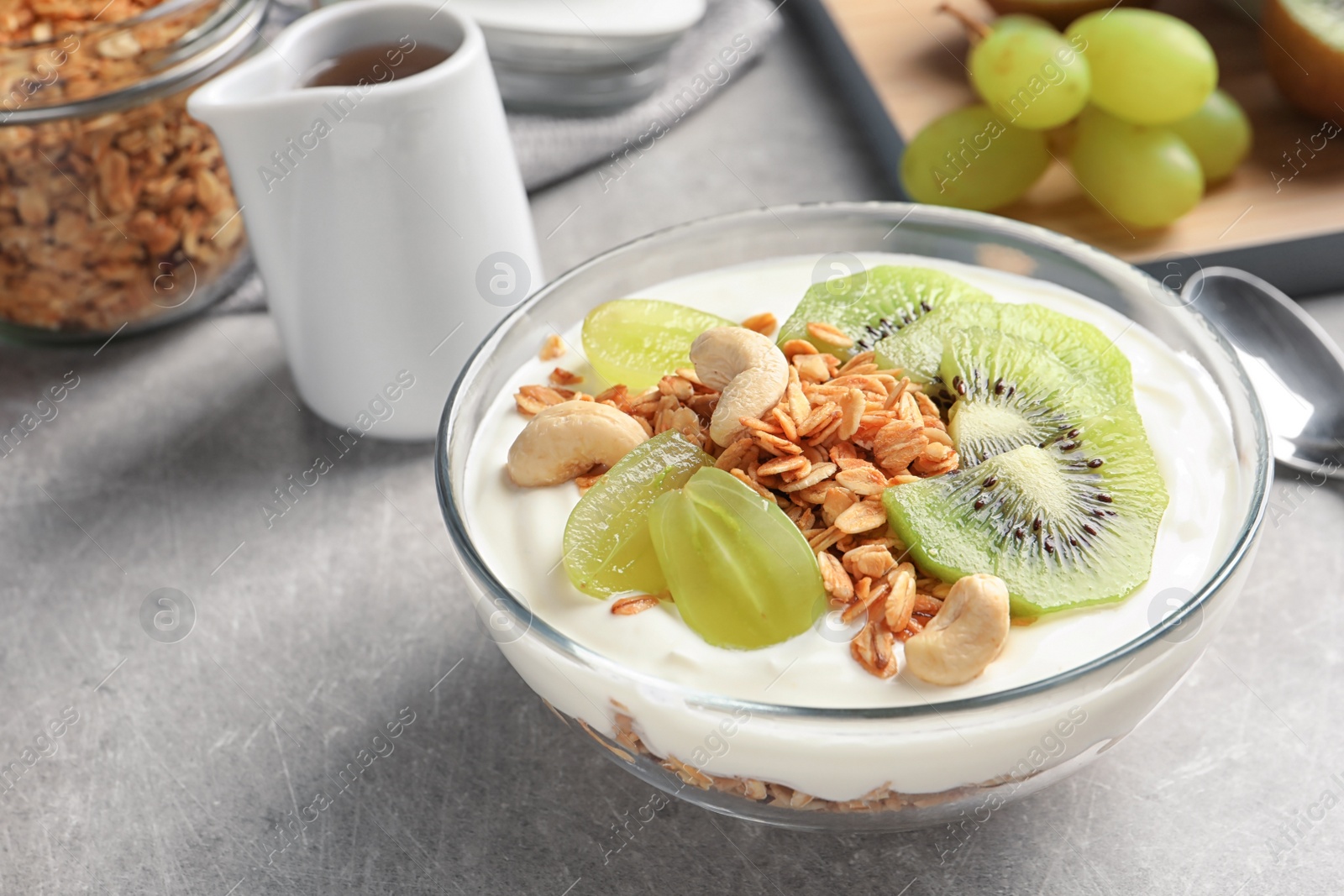 Photo of Bowl with yogurt, fruits and granola on table