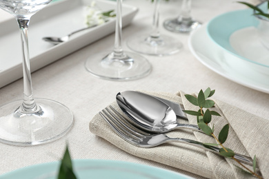 Elegant cutlery with green leaves on table. Festive setting