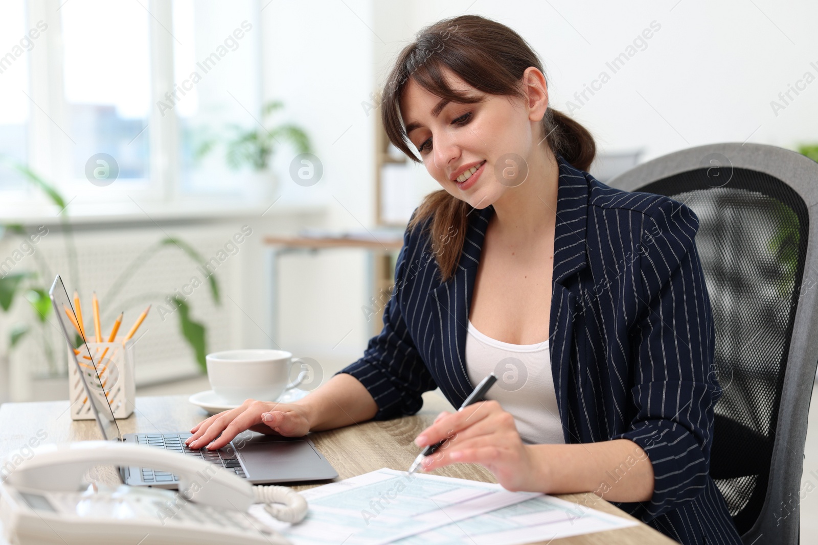 Photo of Smiling secretary working at table in office