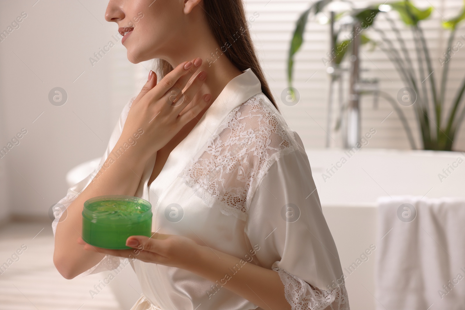 Photo of Young woman applying aloe gel onto her neck in bathroom, closeup