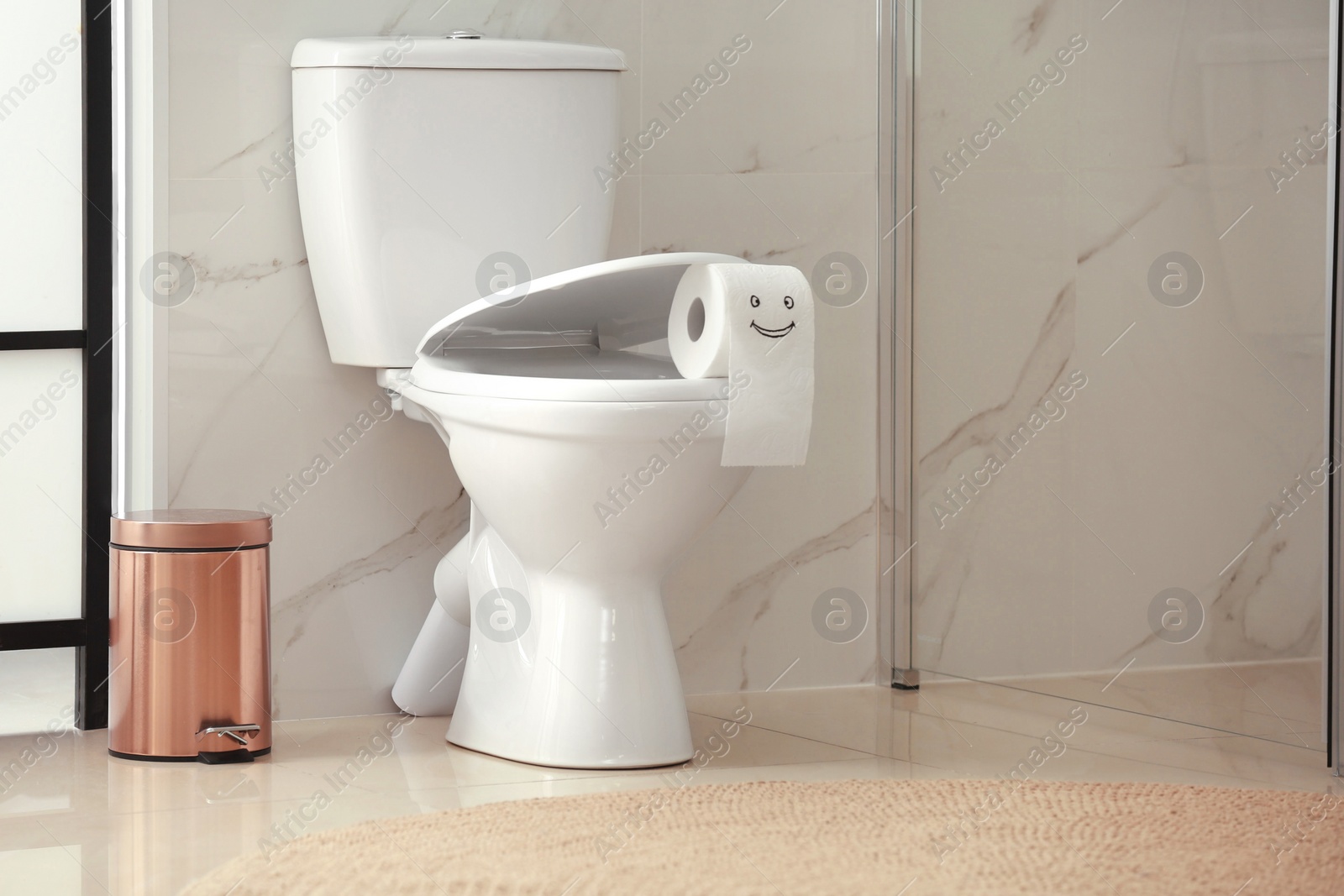 Photo of Roll of paper with funny face on toilet bowl in bathroom