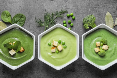 Flat lay composition with different fresh vegetable detox soups made of green peas, broccoli and spinach in dishes on table