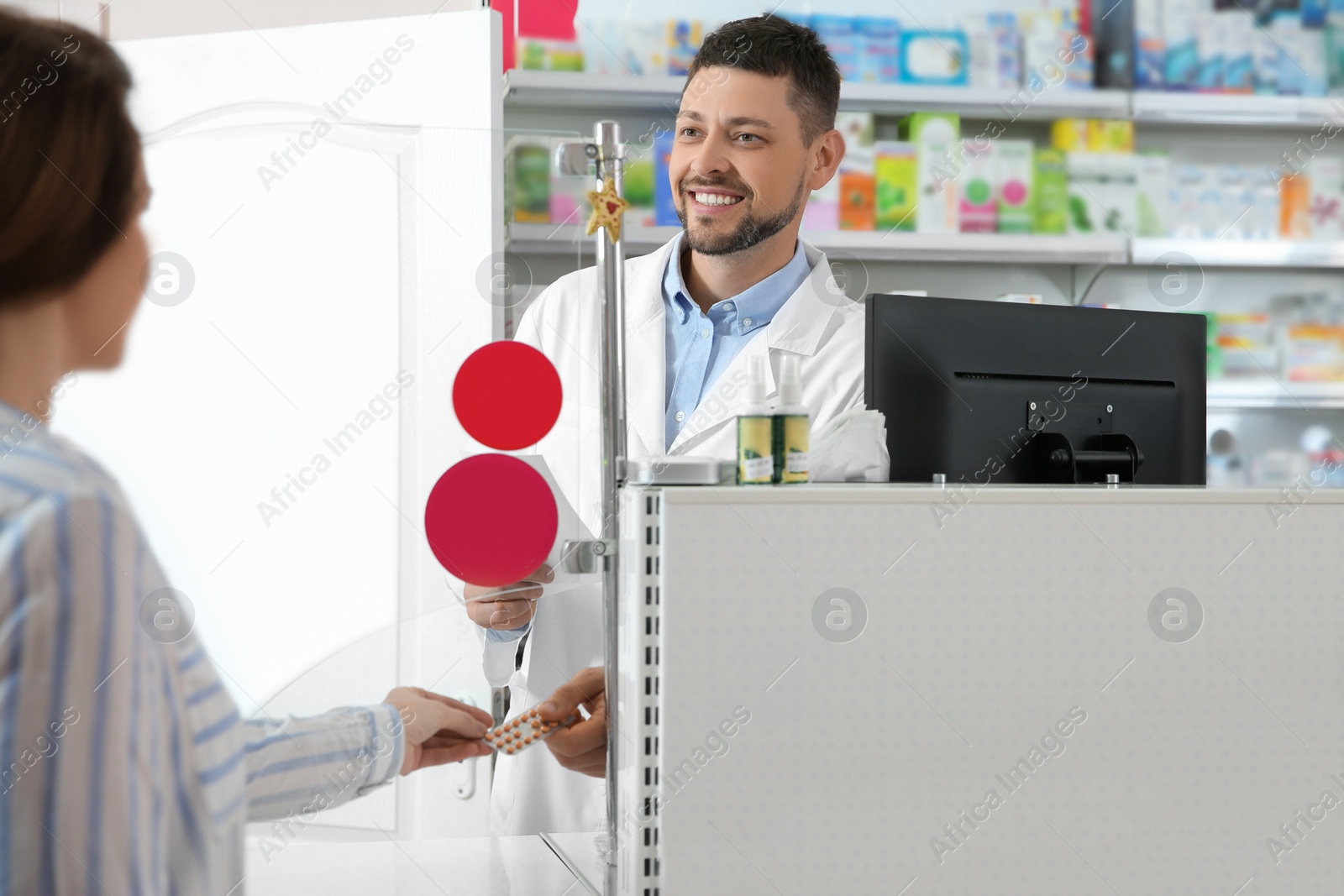 Photo of Professional pharmacist giving pills to customer in drugstore