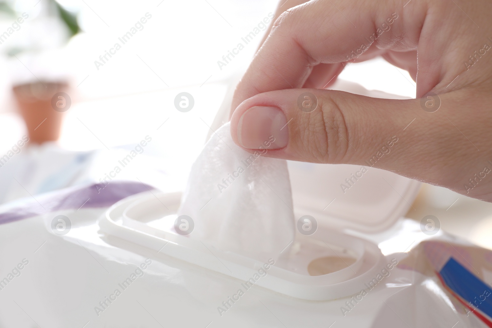 Photo of Woman taking wet wipe from pack on blurred background, closeup